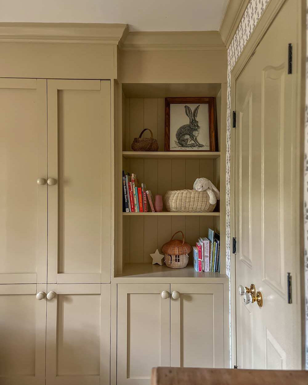 Custom-built IKEA PAX wardrobe hack styled with framed art prints for a bespoke bedroom storage look