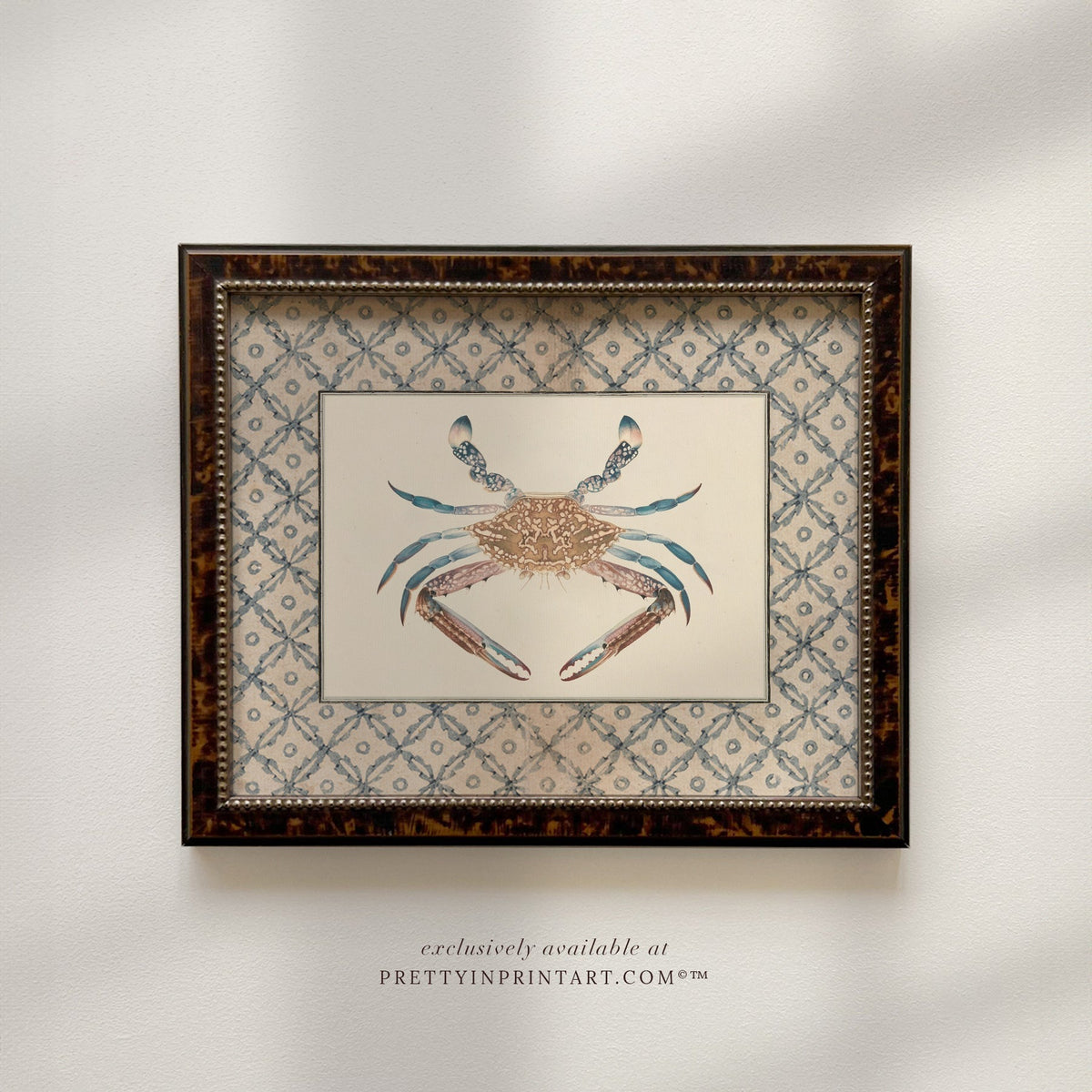 Vintage blue crab art print in a tortoiseshell-style wooden frame, front view